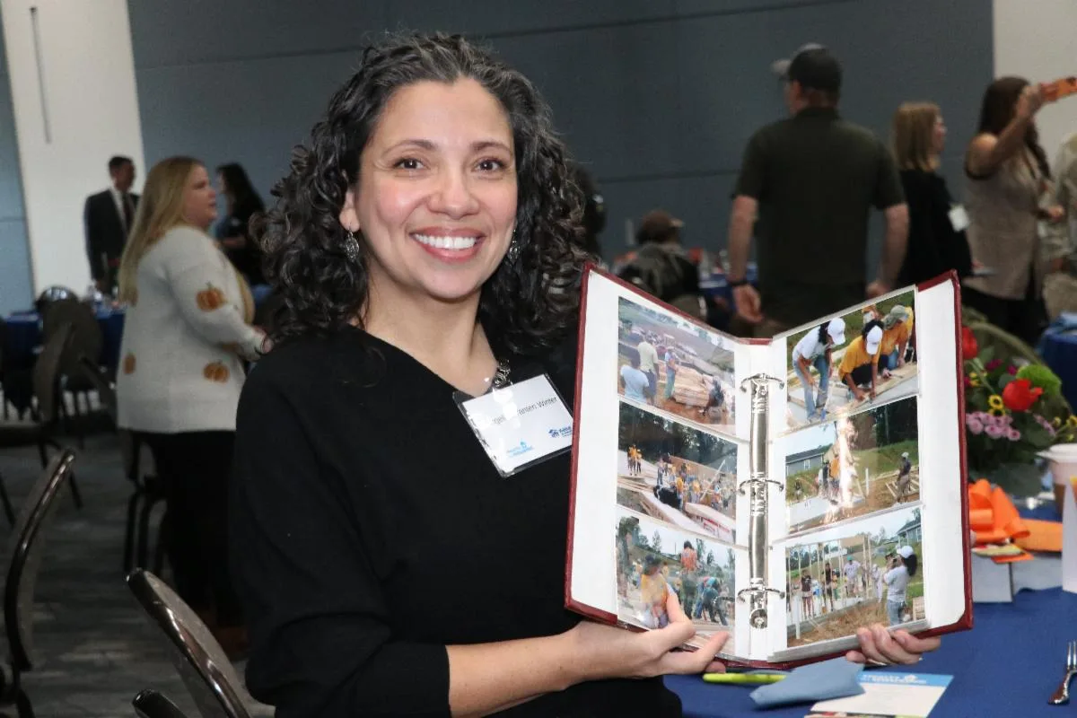 Angelica Yanten Winter holds open a photo album of a Habitat home build