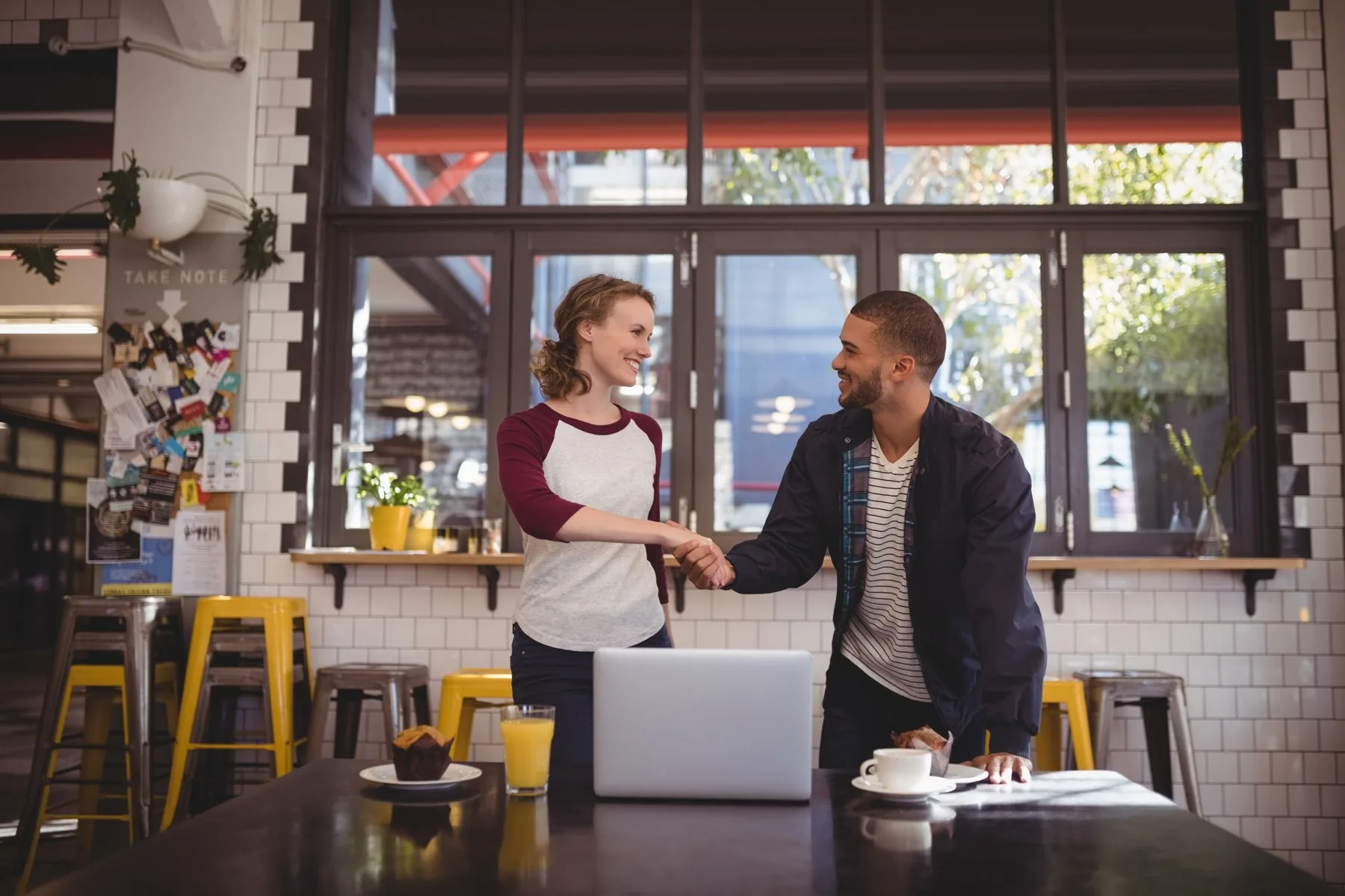 Business handshake at cafe table with laptop